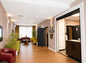 A hotel room with a wooden floor, a sofa, a dining table, and a kitchen area. - City-Hotel Frankfurt (Frankfurt)
