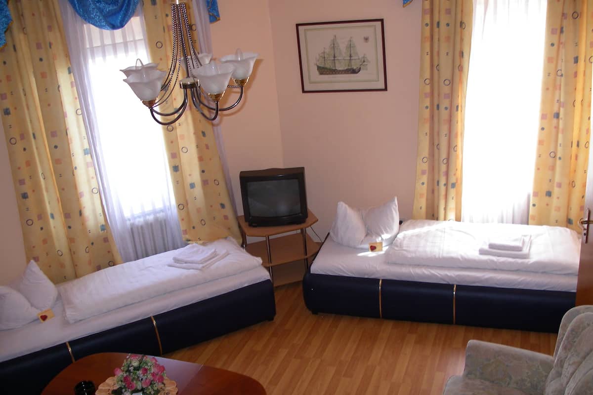 Une chambre d’hôtel avec deux lits, une télévision, un lustre et un tableau au mur.