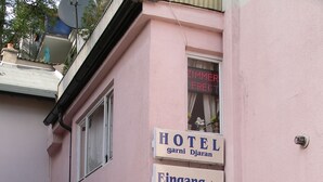 Een hotelentree met een bord waarop 'HOTEL garni Djiran' staat en een pijl die naar de ingang wijst.