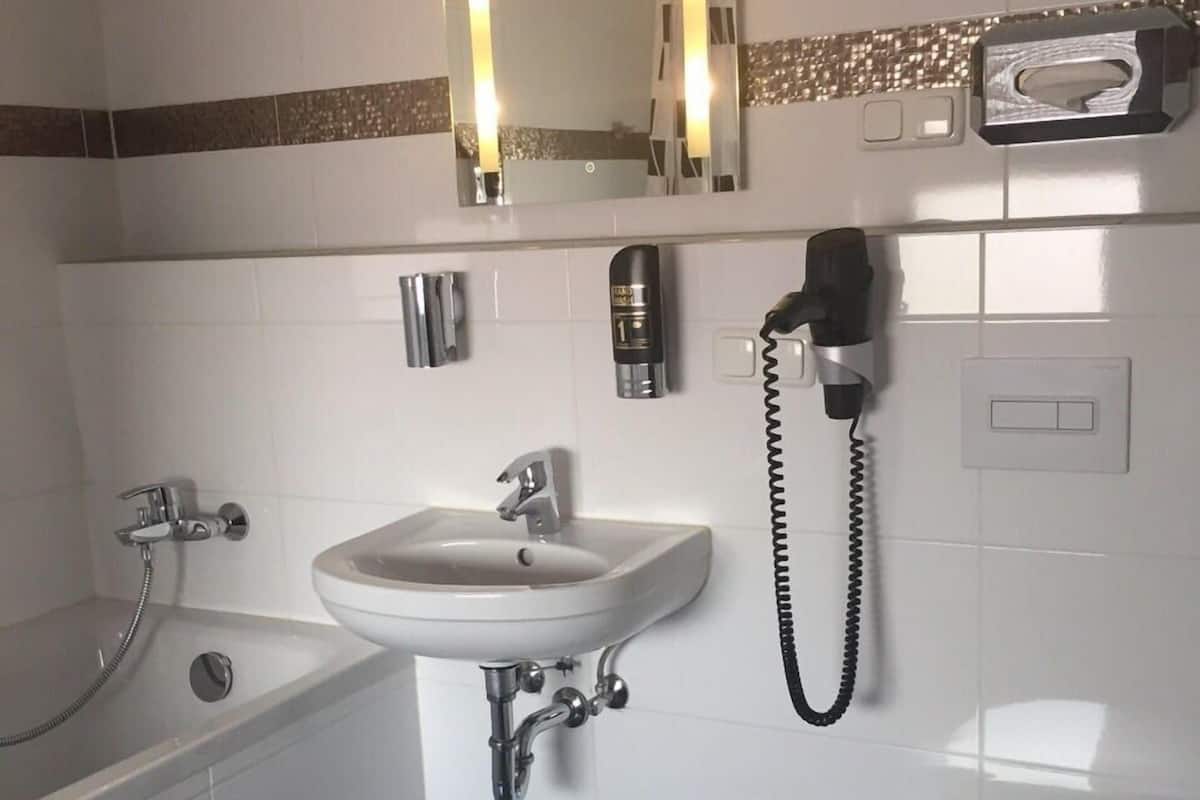 Een bad/douchecombinatie, een haardroger, handdoeken