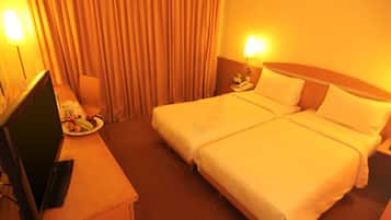 A hotel room with a bed, a desk with a computer, and a lamp.