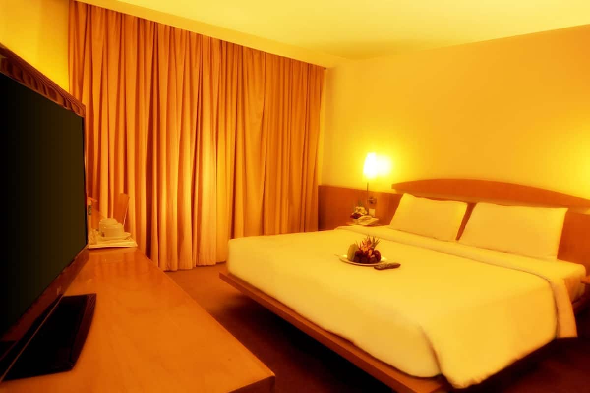 A hotel room with a bed, a desk, and a television.