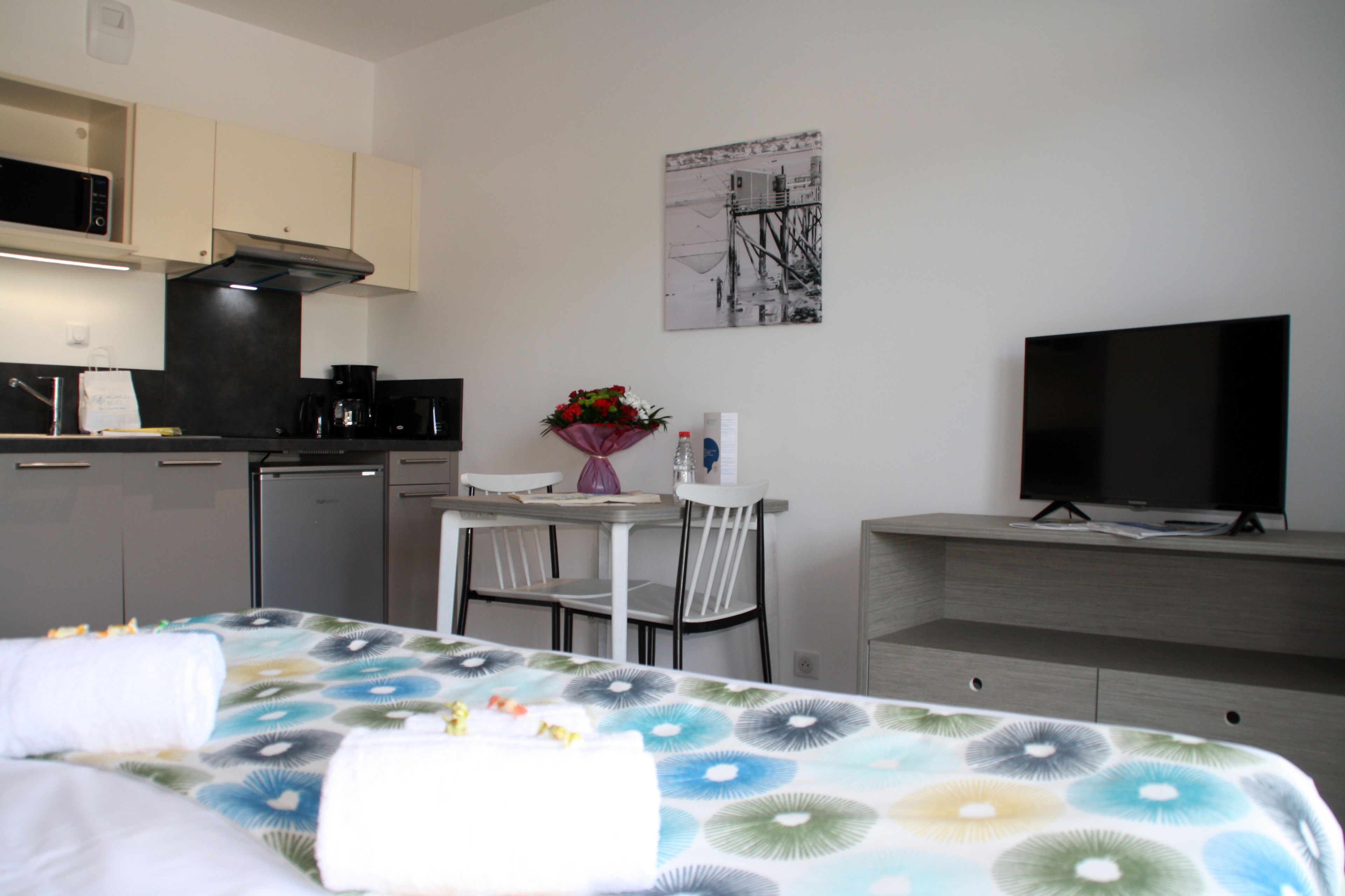Een hotelkamer met een bed, een bureau, een televisie, een magnetron en een koffiezetapparaat.