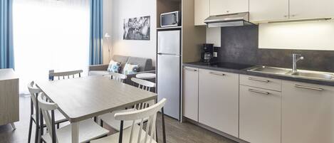 A modern kitchen with a dining area, featuring a microwave, refrigerator, and a coffee maker.