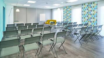 A conference room with rows of foldable chairs, a whiteboard, and a yellow sofa.