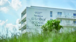 Un edificio moderno con balcones y un cartel que dice "Vacances Bleues Residence LES Coteaux de Jonzac".