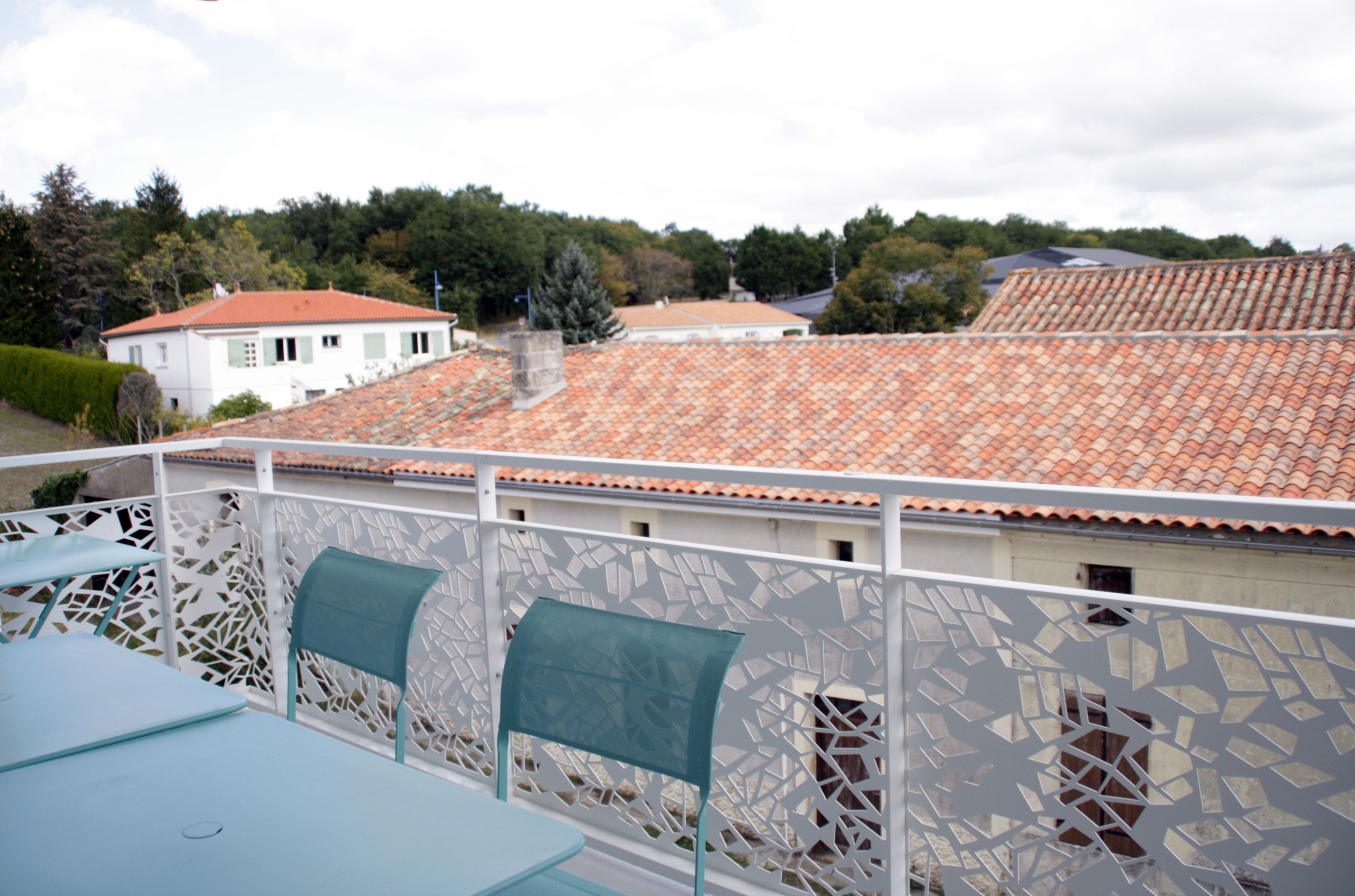 A balcony with a white lattice fence, a table, and two chairs.
