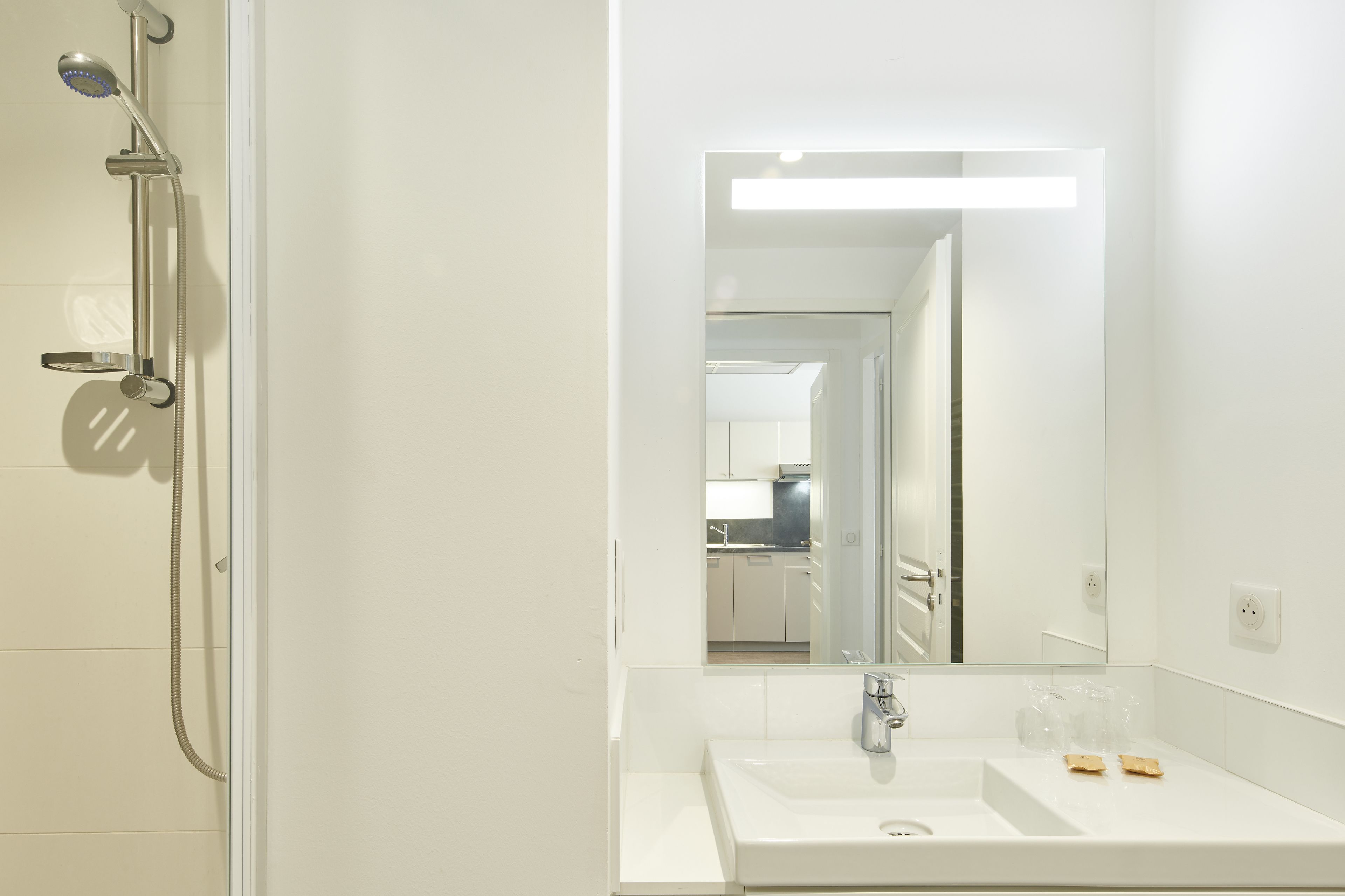 A modern bathroom with a shower, sink, and mirror.