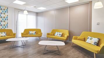 Ein Zimmer mit drei gelben Sofas, einem weißen Tisch und einer Wand mit Muster.