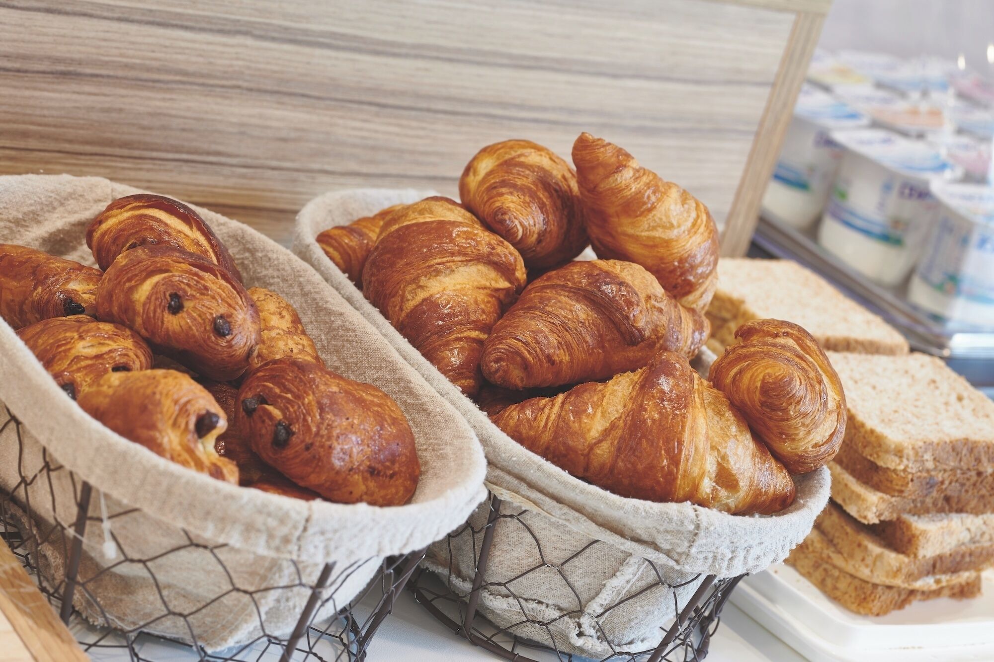 A basket of croissants and bread on a table.