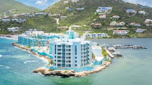 A coastal hotel with multiple buildings, a dock, and a mountainous backdrop.