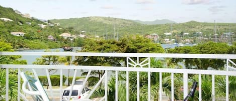 Un balcon avec vue sur un port de plaisance, des bateaux et des collines.