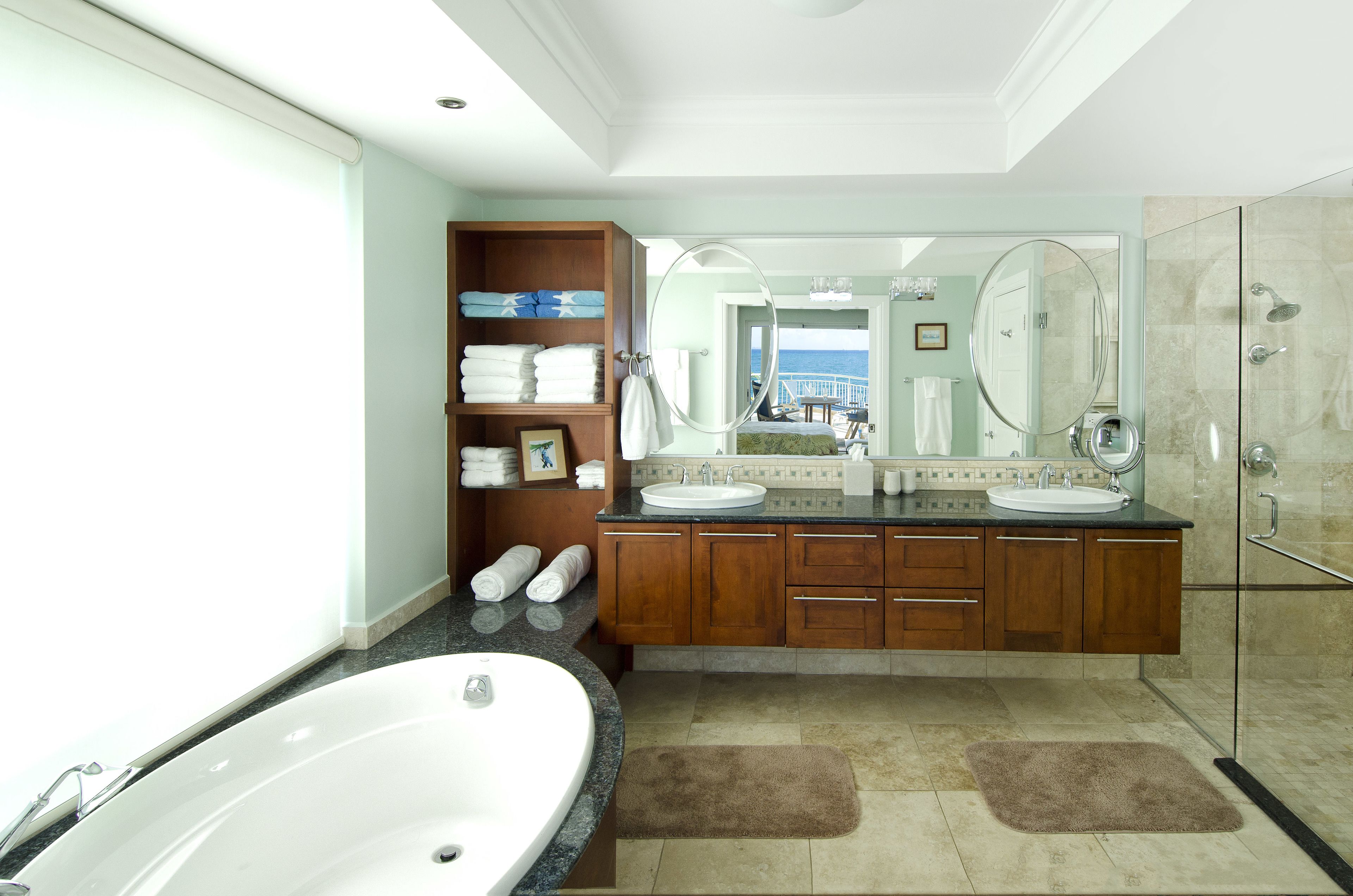 Un baño moderno con una bañera grande, dos lavamanos y una ducha con cerramiento de vidrio.