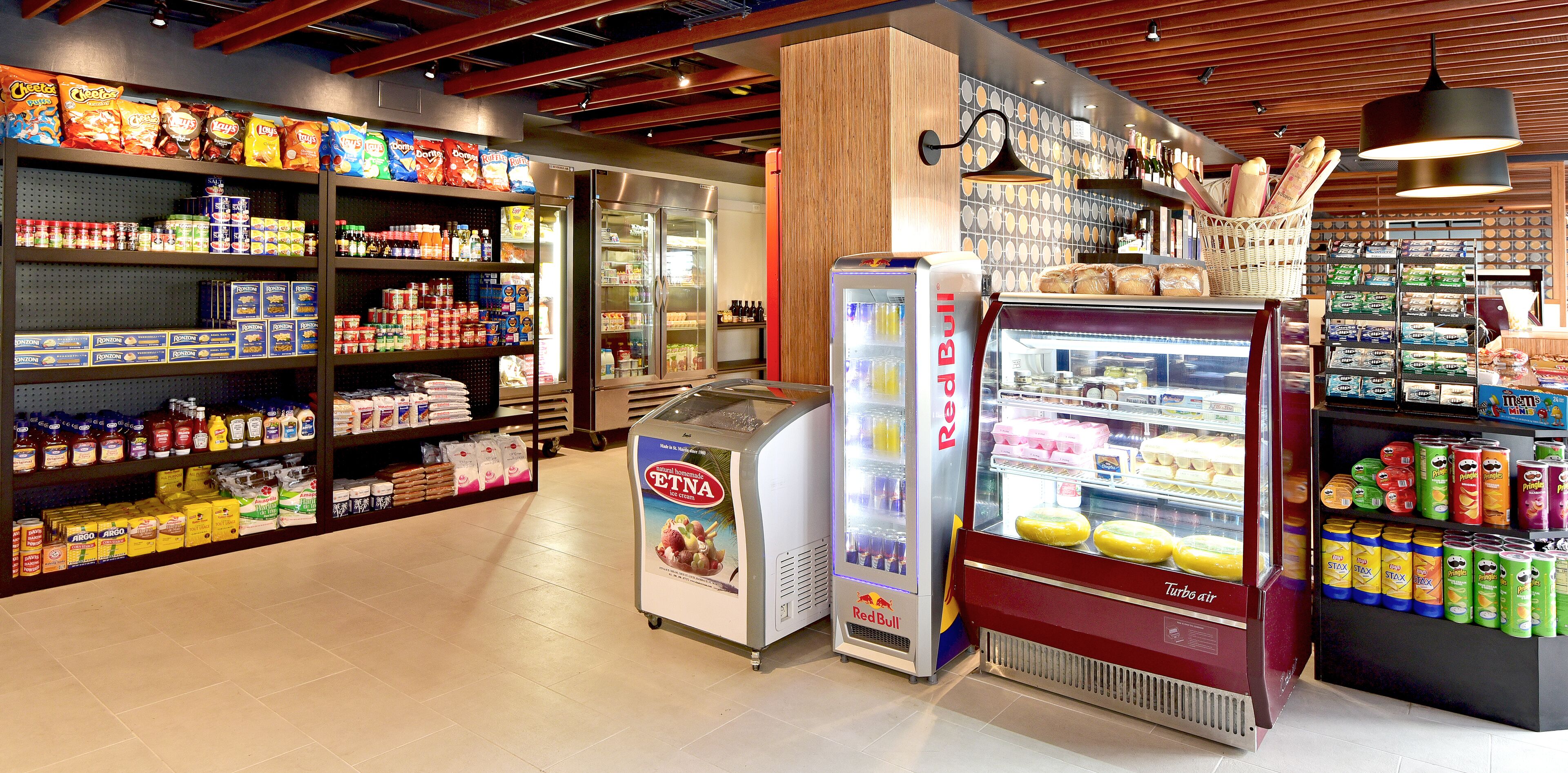 A grocery store interior with refrigerated sections, shelves stocked with snacks, and a Red Bull vending machine.