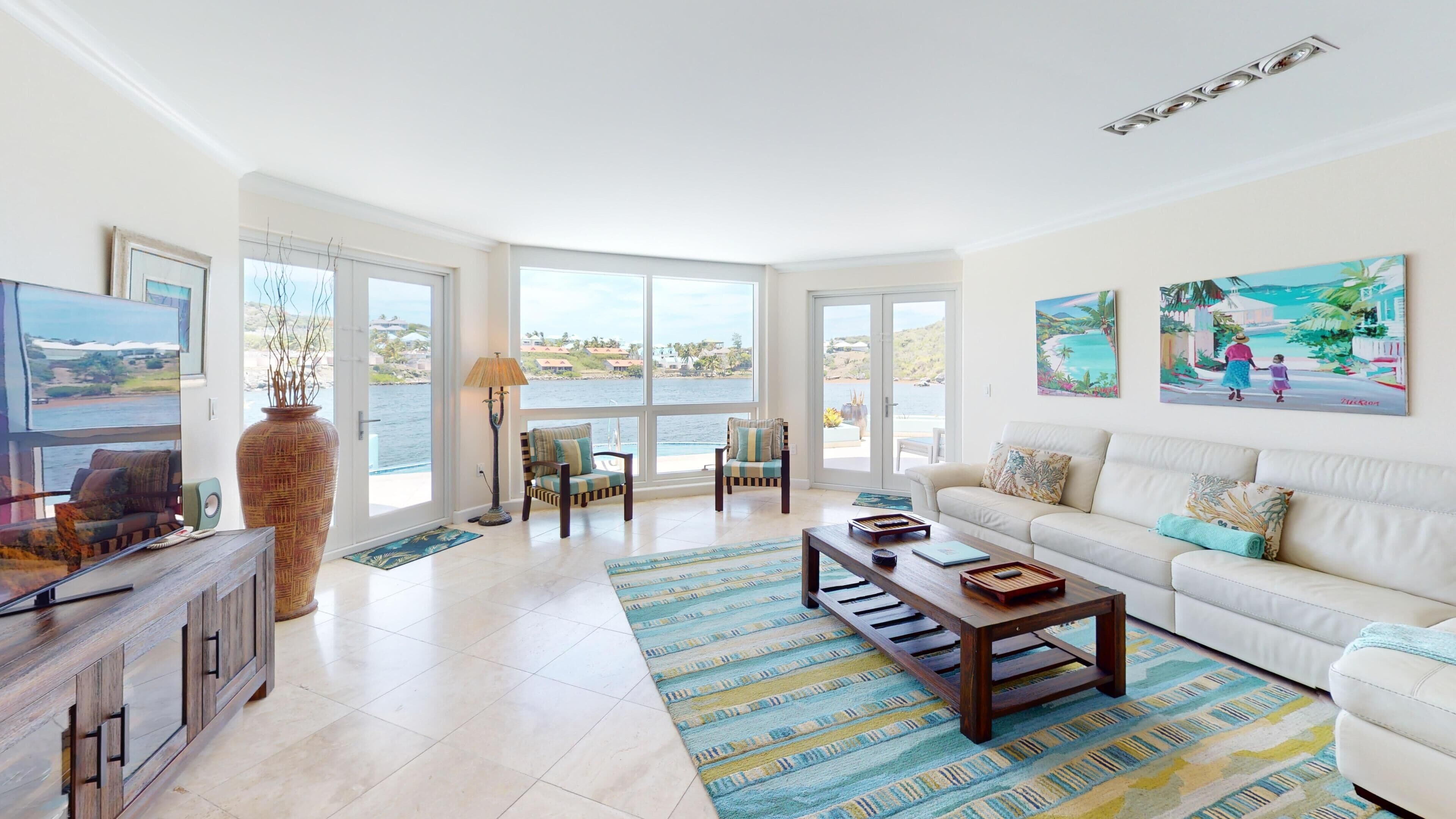 A spacious living room with a large window, a sofa, a coffee table, and a TV.