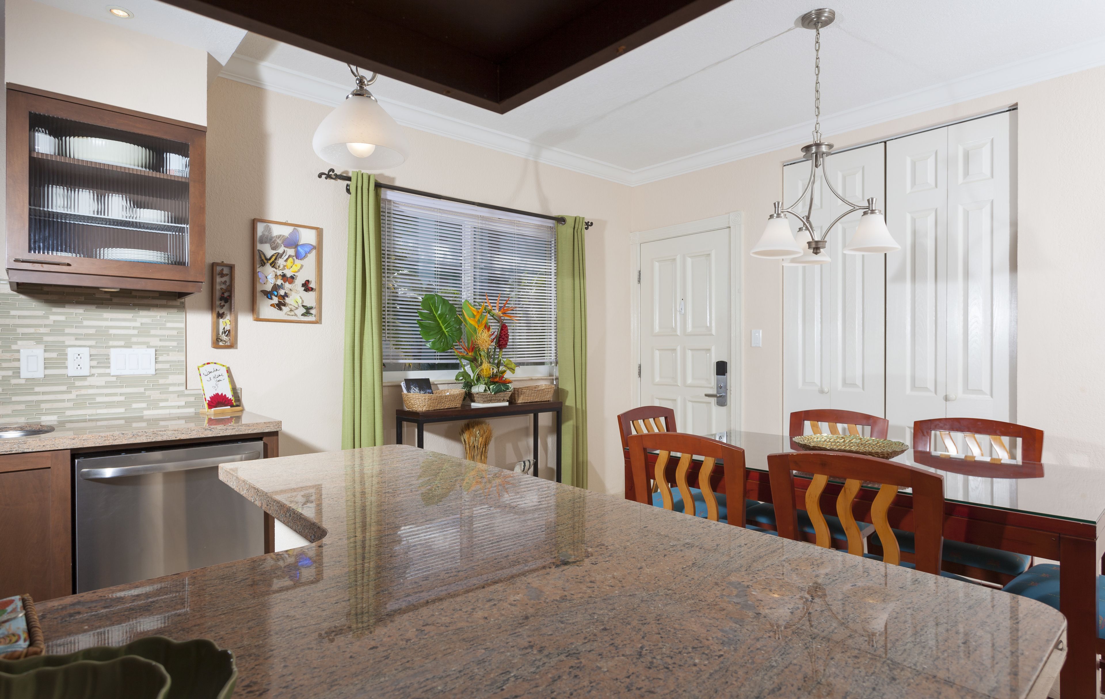 A kitchen with a granite countertop, wooden cabinets, a dishwasher, and a window with blinds.
