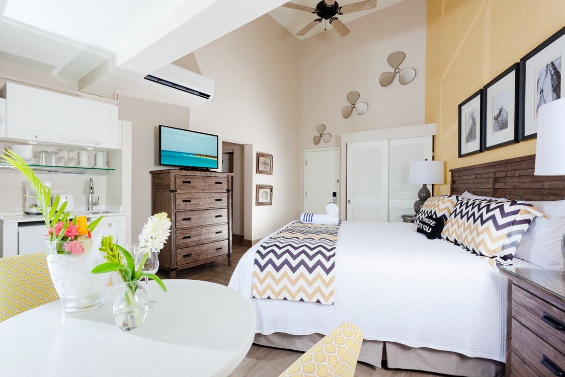 A hotel room with a bed, a TV, a desk, and a dining area.