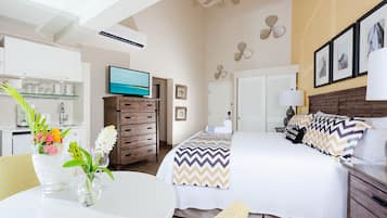 A hotel room with a bed, a TV, a desk, and a dining area.