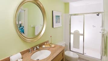 A bathroom with a large mirror, a sink, a toilet, and a glass-enclosed shower.
