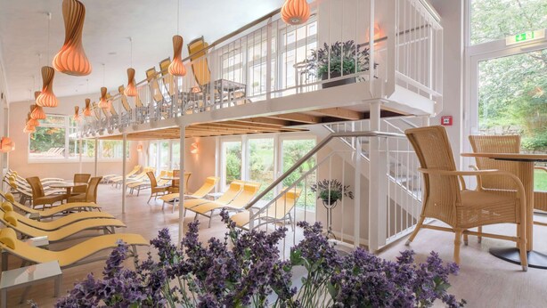 Un hall de hotel de varios niveles con escaleras, zonas de estar y ventanas amplias.