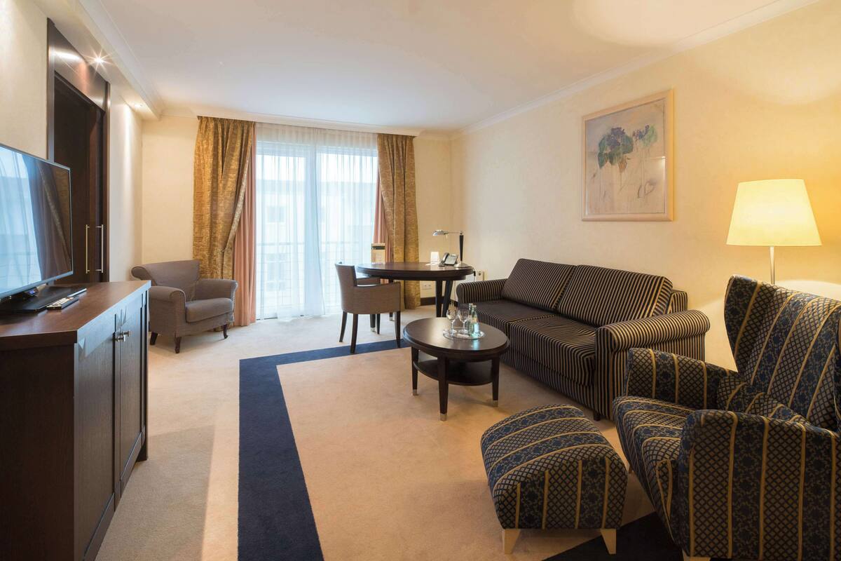 Ein Hotelzimmer mit einer Couch, einem Sessel und einem Fernseher auf einem Schrank.