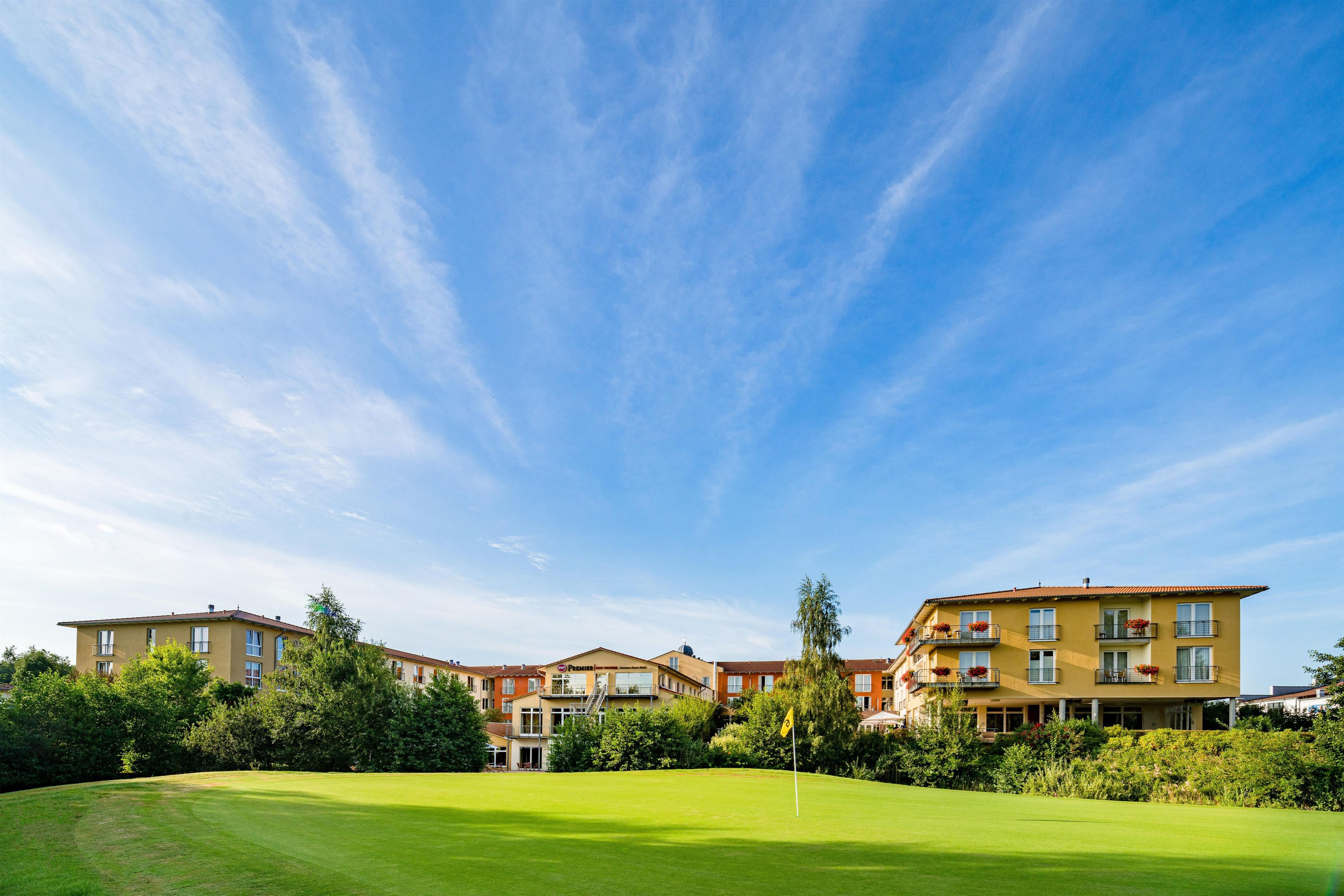 A hotel with multiple floors, a well-maintained lawn, and a clear sky.