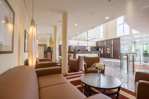 A hotel lobby with a reception desk, seating area, and a view of the outside.