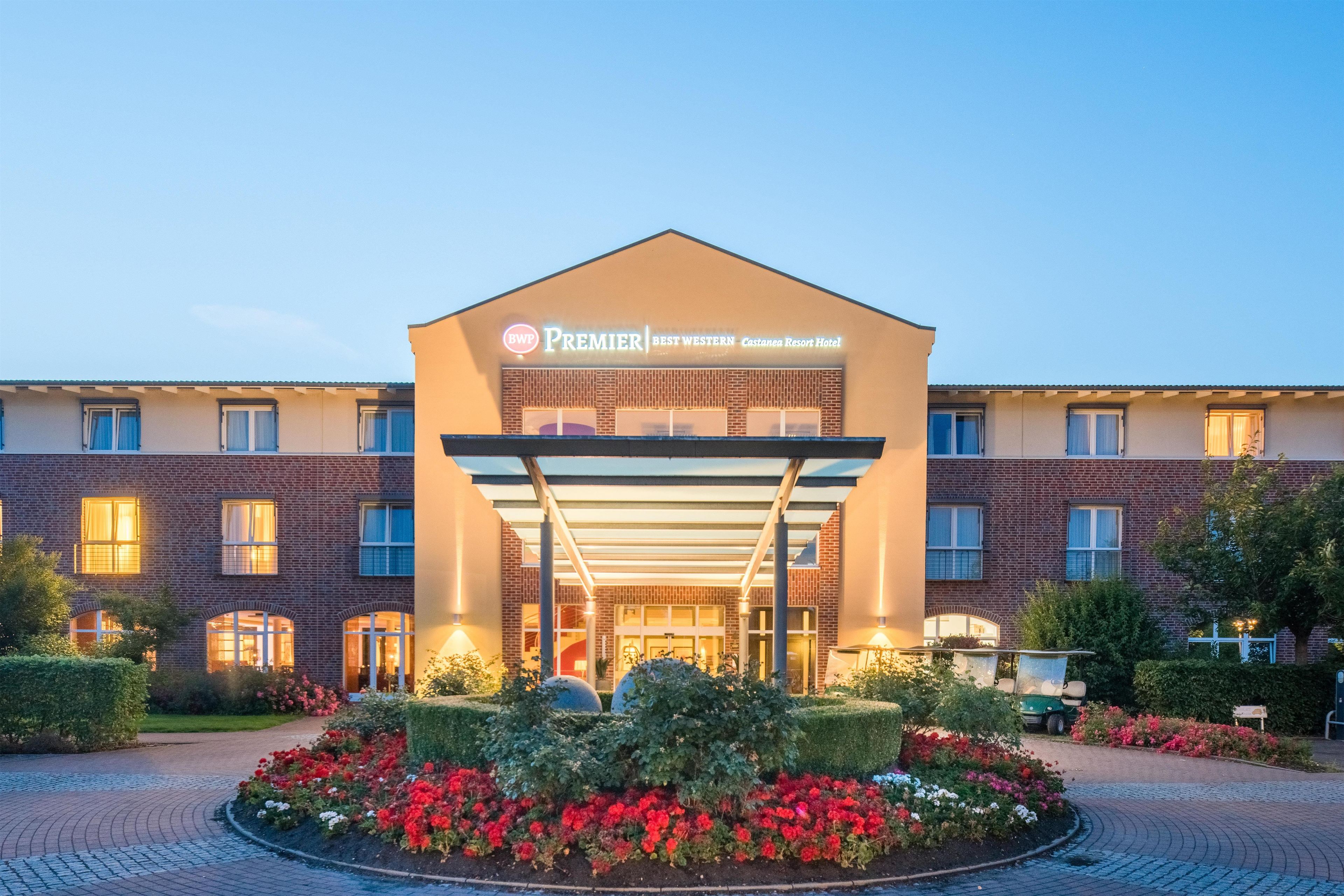 En hotelindgang med et overdækket gelænder, en murstensfacade og et skilt med teksten 'Premier Best Western Castanea Resort Hotel'.