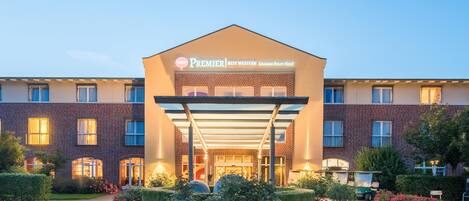 A hotel entrance with a covered walkway, a brick facade, and a sign for 'Premier Best Western Castanea Resort Hotel.'