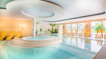 Ein Pool mit kreisförmigem Design, umgeben von gelben Liegestühlen, und ein Wandgemälde mit einer Landschaftsmalerei an der angrenzenden Wand.