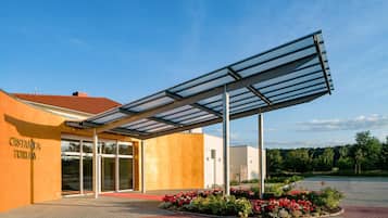 A building with a covered entrance, a sign reading 'CASTANEA FORUM,' and a landscaped area with flowers.