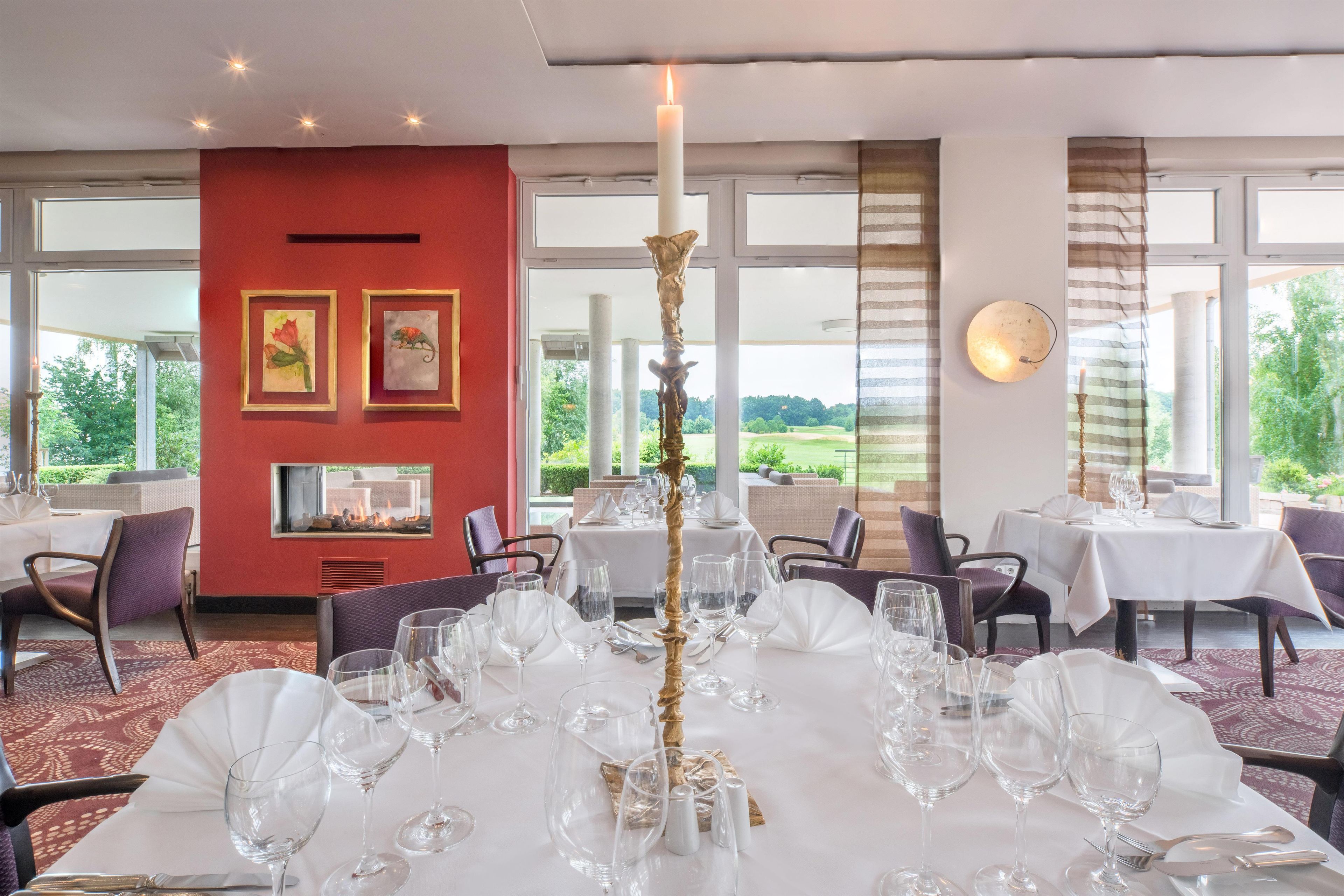 Ein Restaurant mit weiß gedecktem Tisch, Bildern an der Wand und Blick ins Freie.