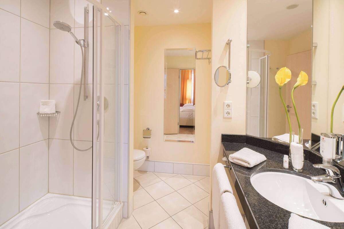 Ein modernes Badezimmer mit einer Duschkabine, einem Waschbecken mit Spiegel und einer Toilette.