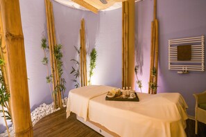 A spa room with a bed, bamboo plants, a tray with spa items, and a white wall. - Best Western Premier Castanea Resort Hotel (Adendorf)