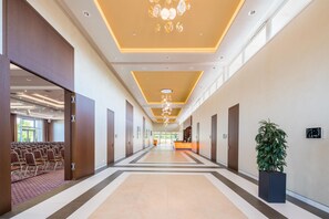 A hotel corridor with a reception desk, seating area, and a large potted plant. - Best Western Premier Castanea Resort Hotel (Adendorf)