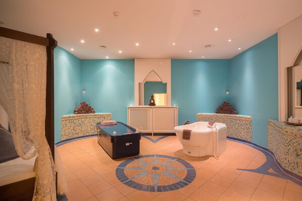 A spa room with a massage table, a hot tub, and a decorative tiled floor. - Best Western Premier Castanea Resort Hotel (Adendorf)