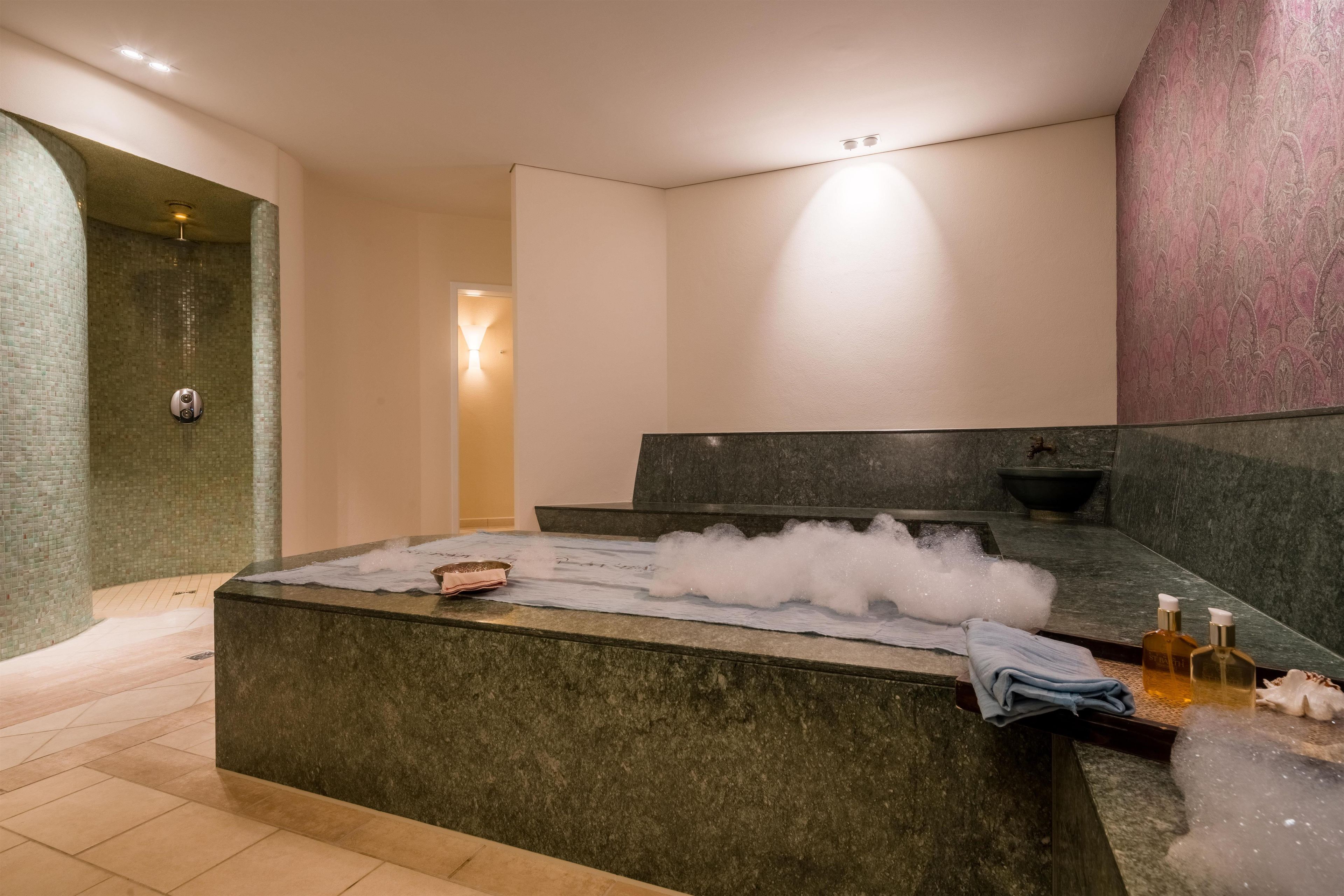 A spa room with a marble reception desk, a shower area, and a wall with a textured pattern.