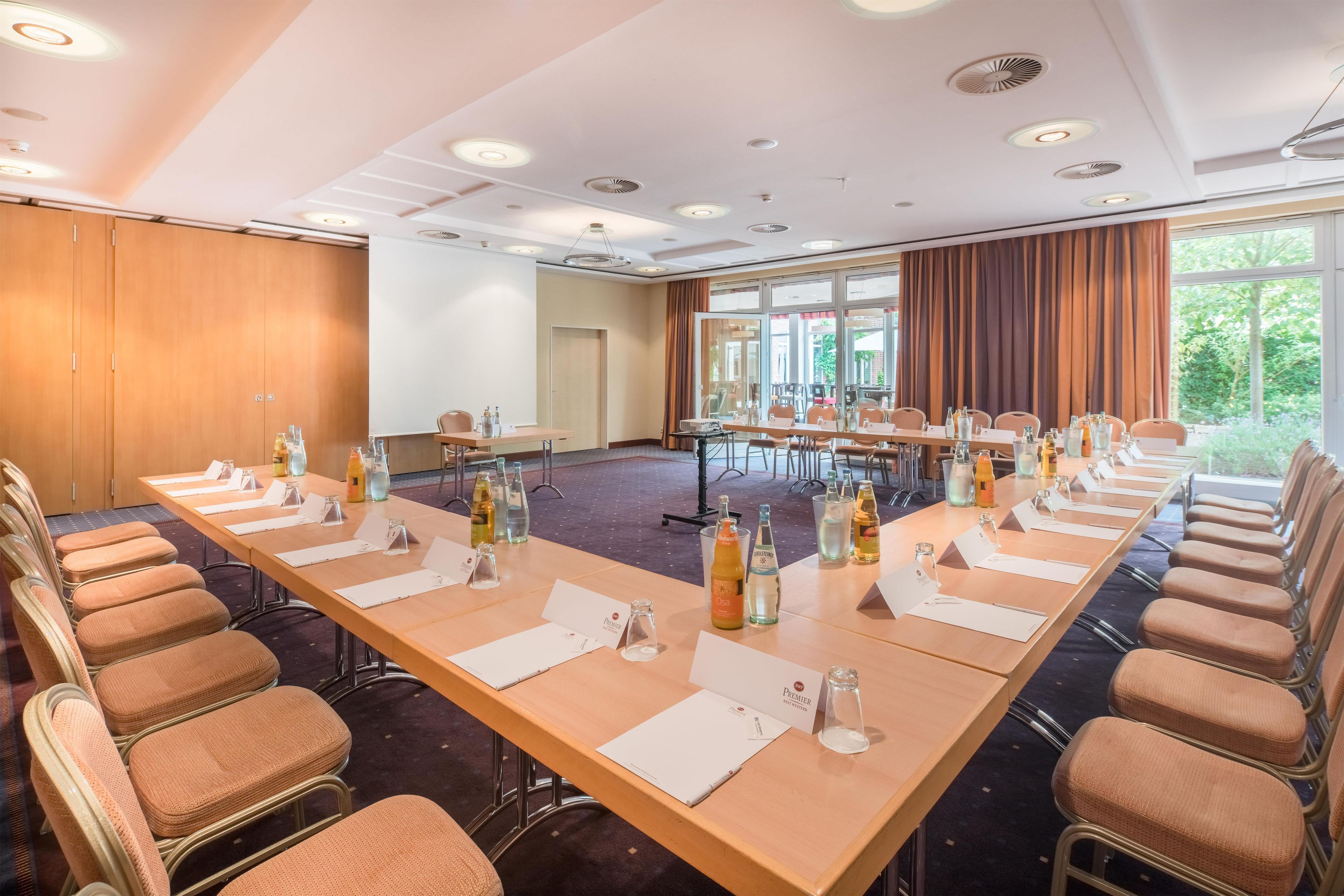 A conference room with long tables, chairs, nameplates, and water bottles.
