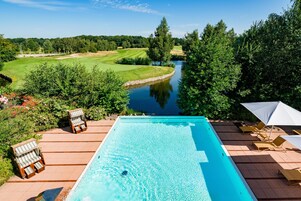 A swimming pool with a view of a golf course and a river.