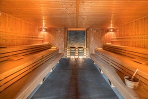 A sauna with wooden benches and a central stone wall. - Best Western Premier Castanea Resort Hotel (Adendorf)