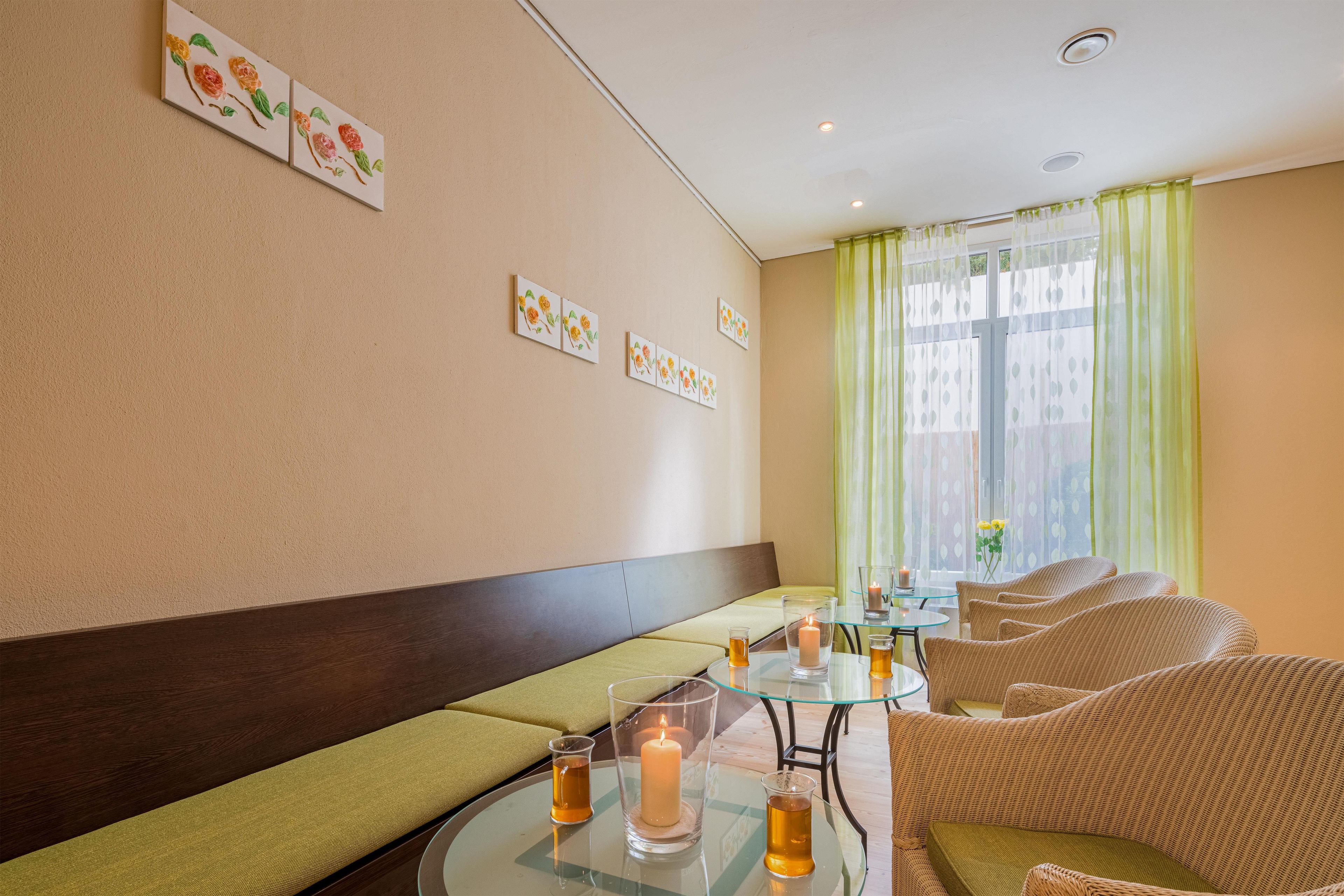 A room with a sofa, a glass table with candles, and artwork on the wall.