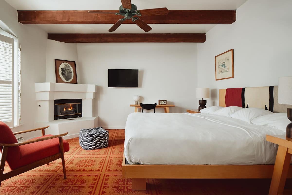 A hotel room with a bed, a fireplace, a television, a desk, and a chair.
