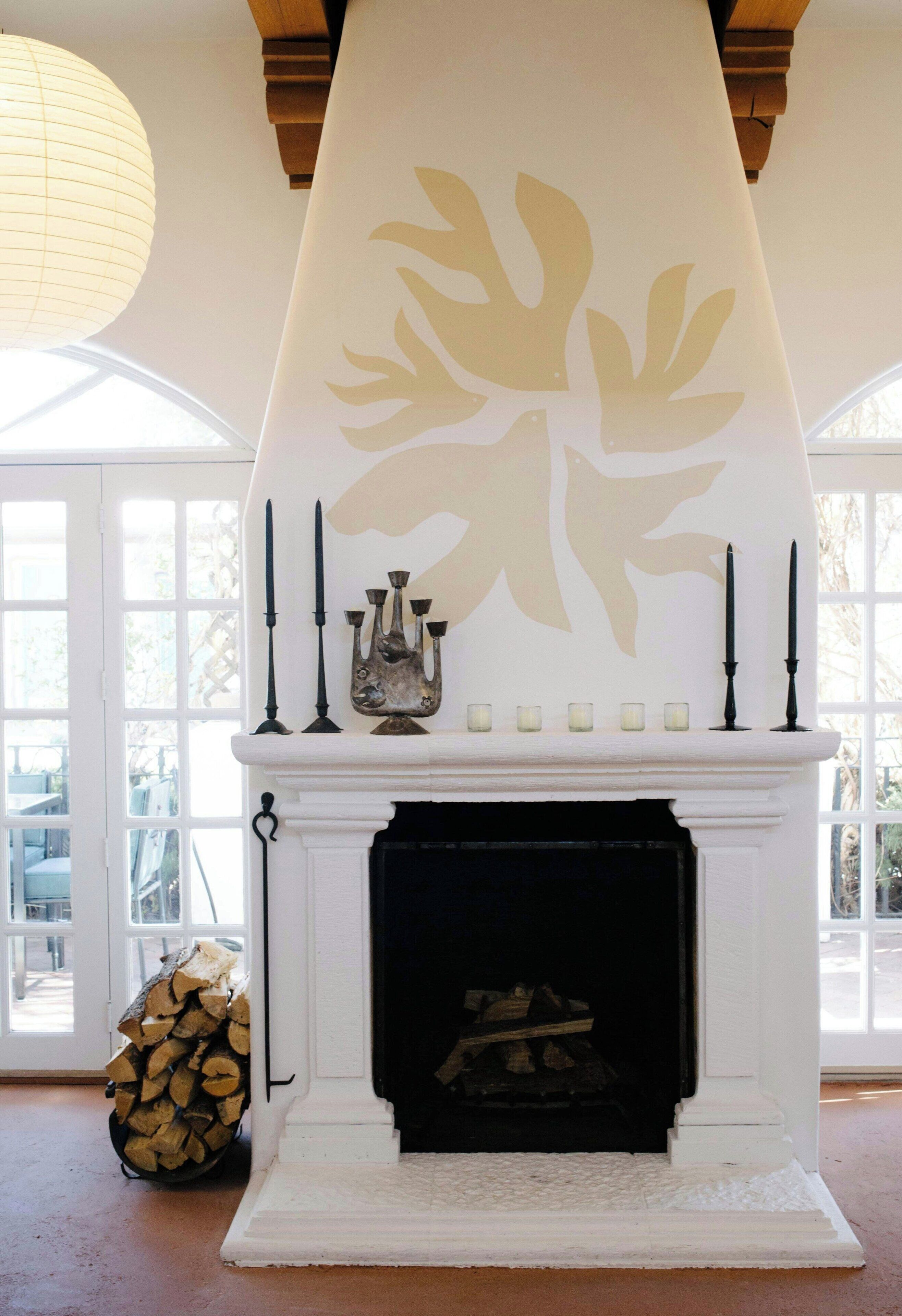 A fireplace with a decorative mantel, a candelabra, and a stack of firewood.