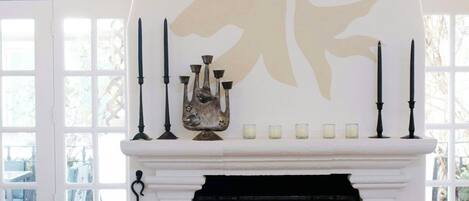 A fireplace with a decorative mantel, a candelabra, and a stack of firewood.
