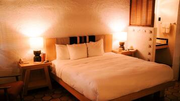 Un dormitorio con una cama grande, dos mesitas de noche con lámparas, un cabecero de madera y suelo de baldosas.
