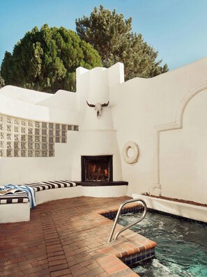 A pool area with a stone fireplace, a bull skull decoration, and a lifebuoy on the wall.