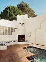 Un área de piscina con una chimenea de piedra, una decoración de cráneo de toro y un flotador en la pared.