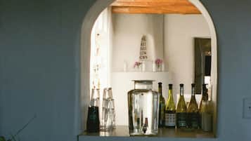A bar area with a wooden ceiling and a white wall. There are bottles and glasses on the counter.