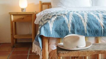 A cozy bedroom with a bed, a bedside table with a lamp, and a wooden bench.