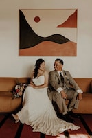 Una pareja sentada en un sofá con un cuadro abstracto grande sobre ellos.